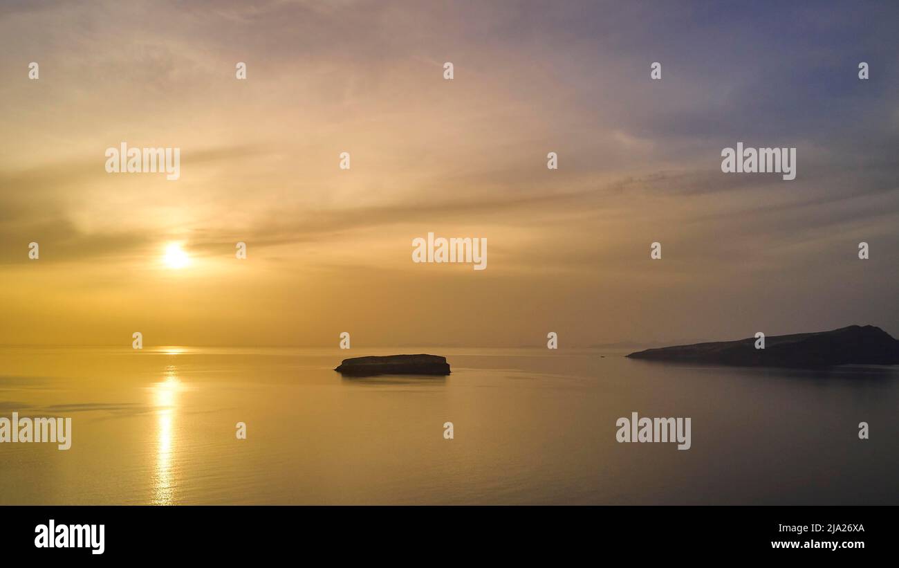 Coucher de soleil, lumière dorée, pointe sud-ouest de l'île, ciel nuageux, île Rocky, île de Santorini, Cyclades, Grèce Banque D'Images