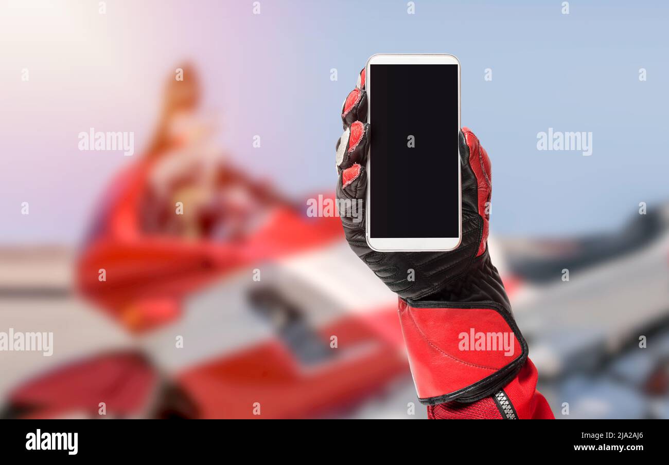 Smartphone Biker portable avec écran vierge, image rognée, espace de copie, écran vide pour le design graphique avec une moto en arrière-plan Banque D'Images