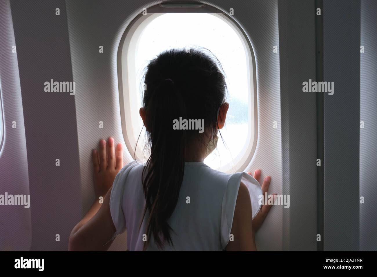 Petite fille mignonne voyageant à bord d'un avion. Enfant fille regardant la vue aérienne du ciel et nuage à l'extérieur de la fenêtre d'avion tout en étant assis sur le siège d'avion. tra Banque D'Images