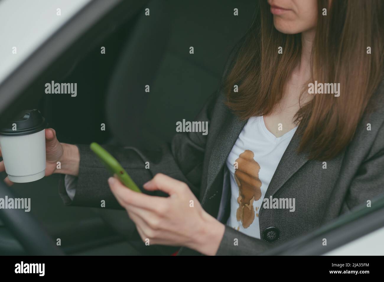 Une femme a renversé du café chaud sur elle-même pendant qu'elle a envoyé des textos en conduisant. Tâches quotidiennes sales Banque D'Images