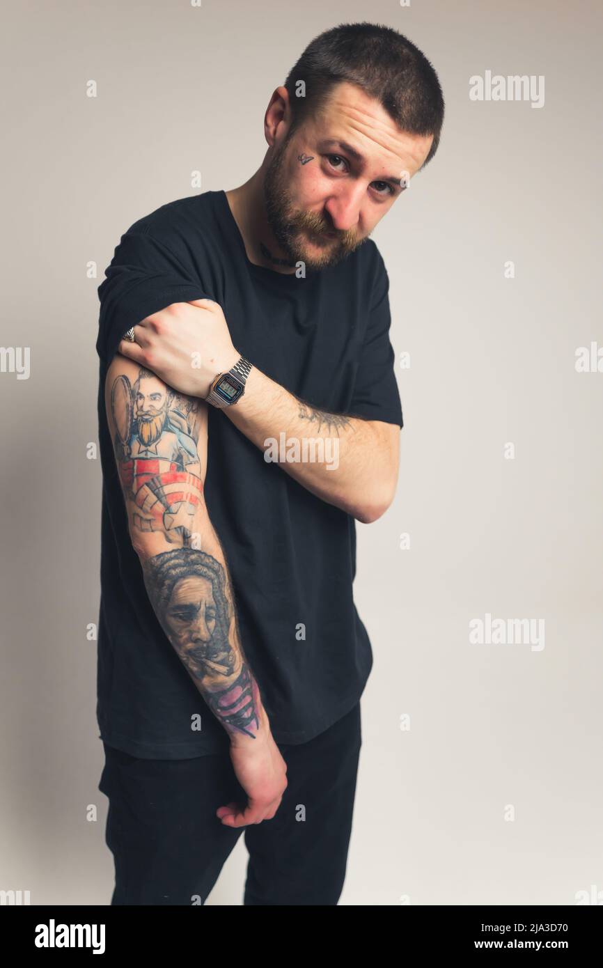 Le millénaire européen en vêtements noirs montre son bras tatoué à la caméra cow-boy tourné gris fond studio tourné . Photo de haute qualité Banque D'Images