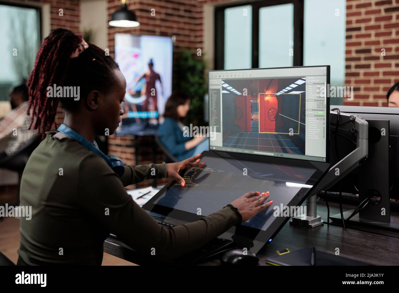 Concepteur de jeux assis dans un espace de travail de bureau tout en travaillant sur l'environnement et les détails de niveau. L'employé du département de production développe des mécanismes de jeu afin d'atteindre le réalisme. Banque D'Images