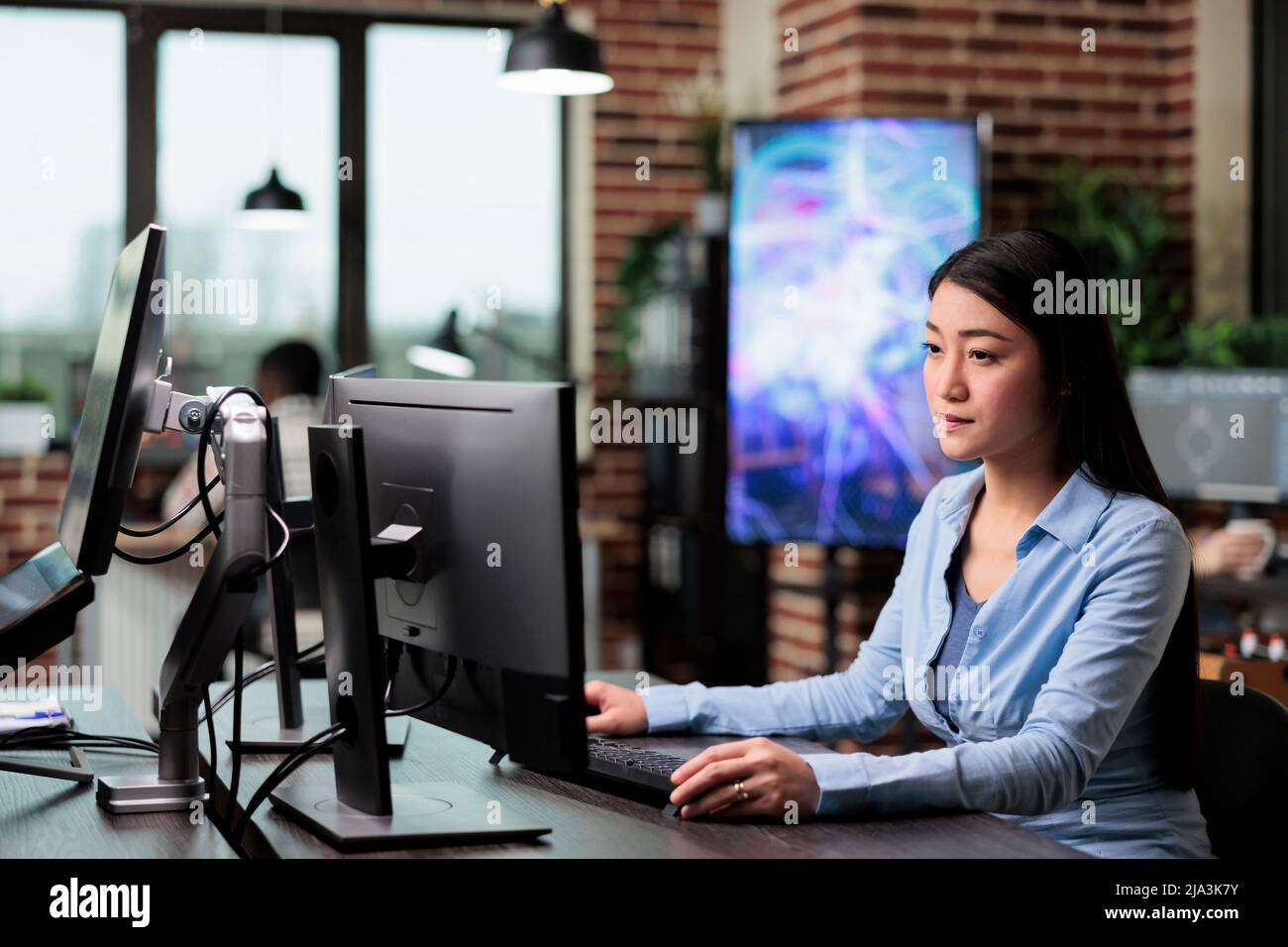 Employé de l'agence créative travaillant à développer un projet numérique tout en étant assis à son bureau. Bureau de l'entreprise travailleur professionnel confiant assis dans l'espace de travail en utilisant le bureau de l'ordinateur pour créer des graphiques. Banque D'Images