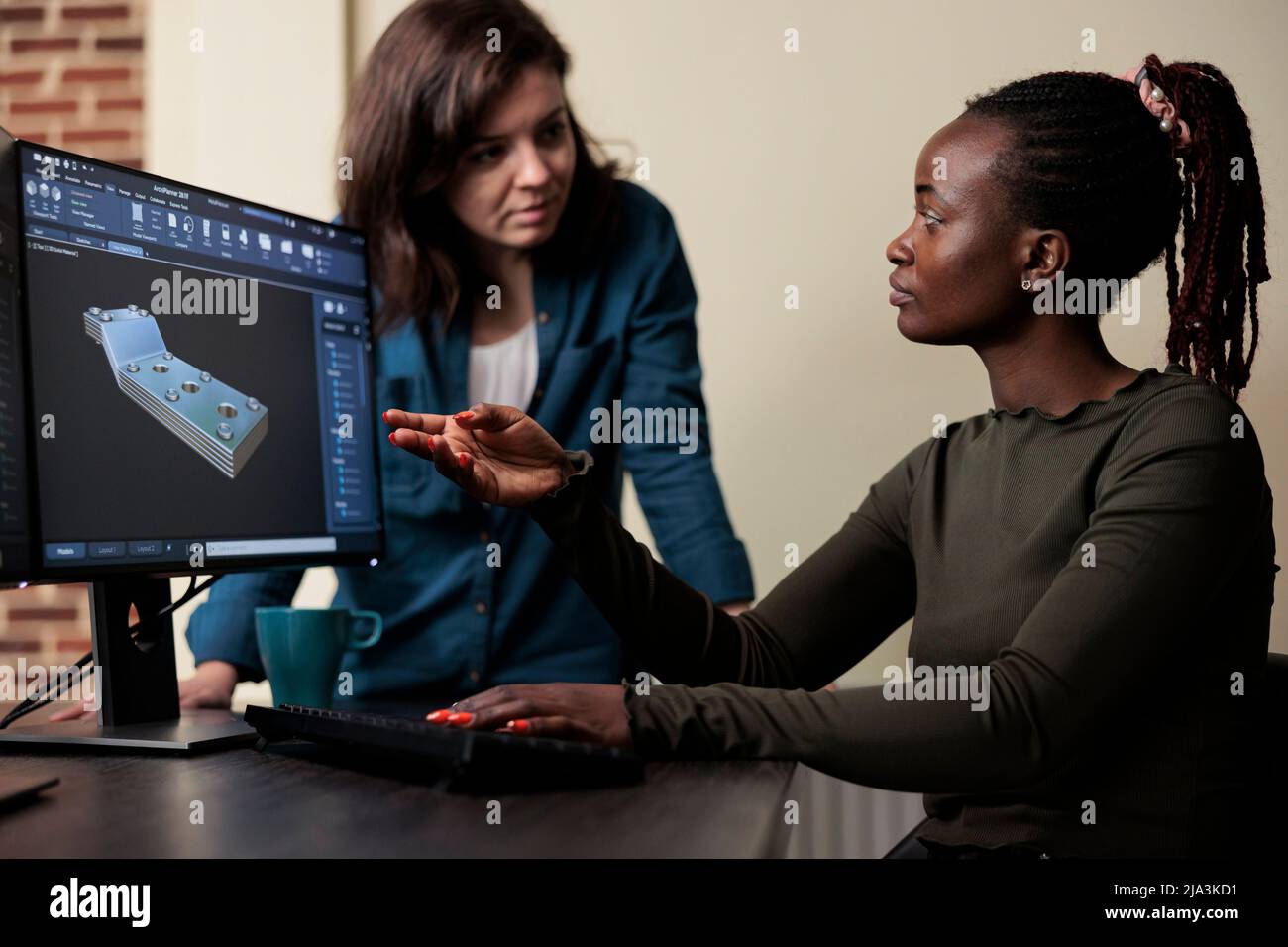 3D artiste numérique collaborant avec un collègue afin de résoudre des difficultés techniques. Le chef d'équipe du service de production indique un problème de géométrie du maillage et fournit une solution à un collègue. Banque D'Images