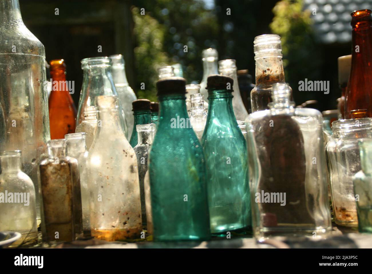 Russie, Musée en plein air d'Izborsk. 16 juin 2017. Exposition des bouteilles en verre rétro vintage multicolore dans la cour d'une ancienne maison. Banque D'Images