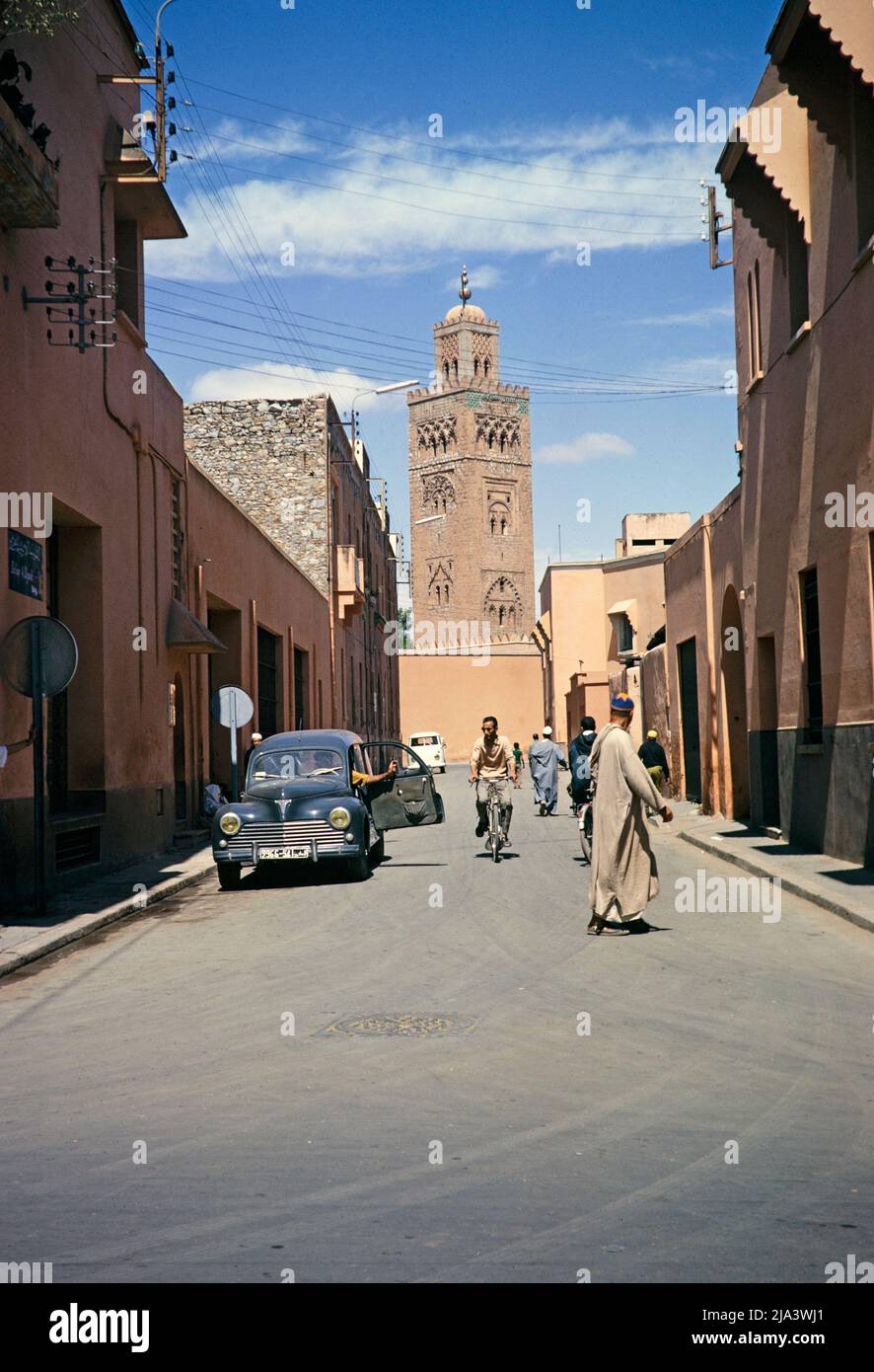 Peugeot 203 voiture dans la rue avec Koutoubia ou Kutubiyya mosquée, Marrakech, Maroc, Afrique du Nord 1971 Banque D'Images