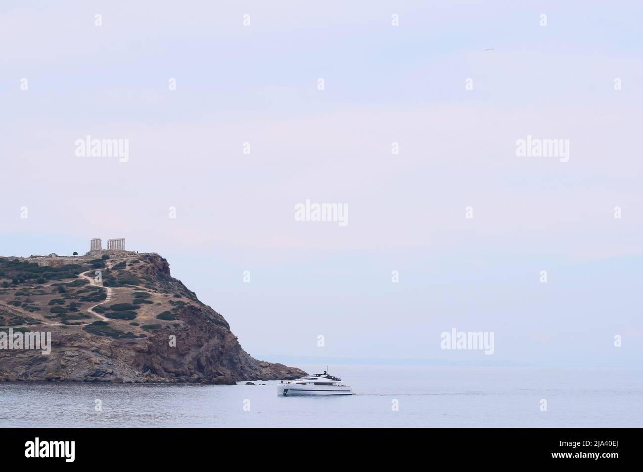 Ancien temple de Poséidon au cap Sounio, Grèce. Roche, mer et un bateau Banque D'Images