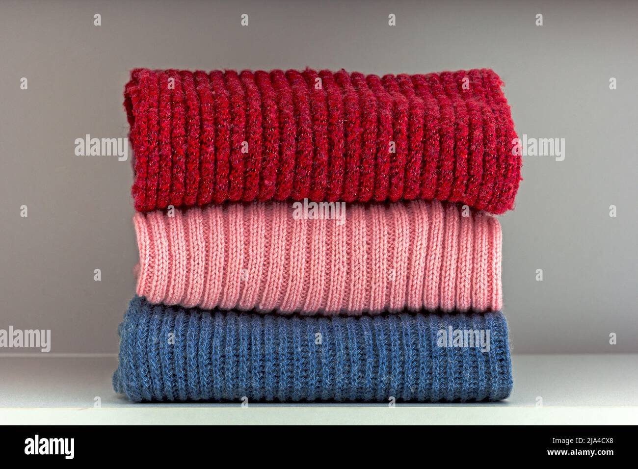 Pile de tissus de laine rouge, rose et bleue sur la tablette de la garde-robe blanche Banque D'Images