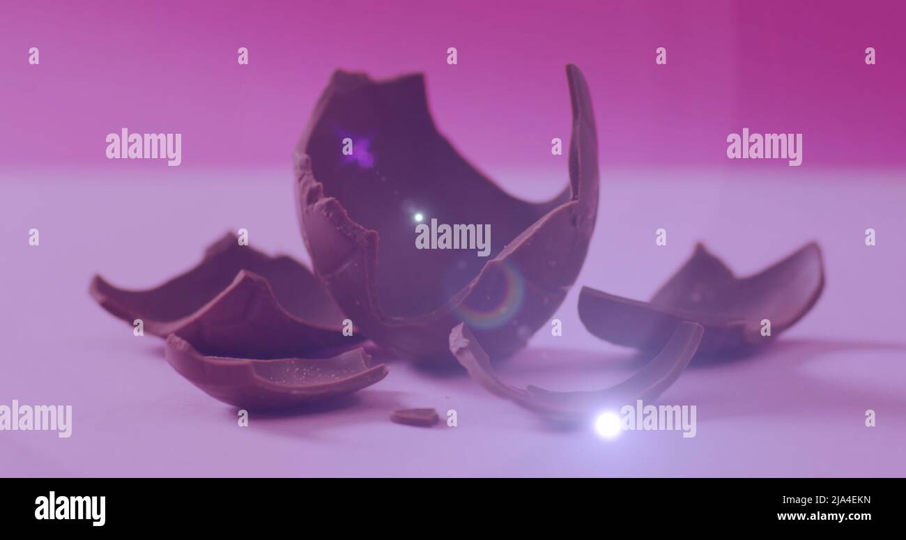 Image de lumière sur un œuf de chocolat cassé sur fond rose Banque D'Images