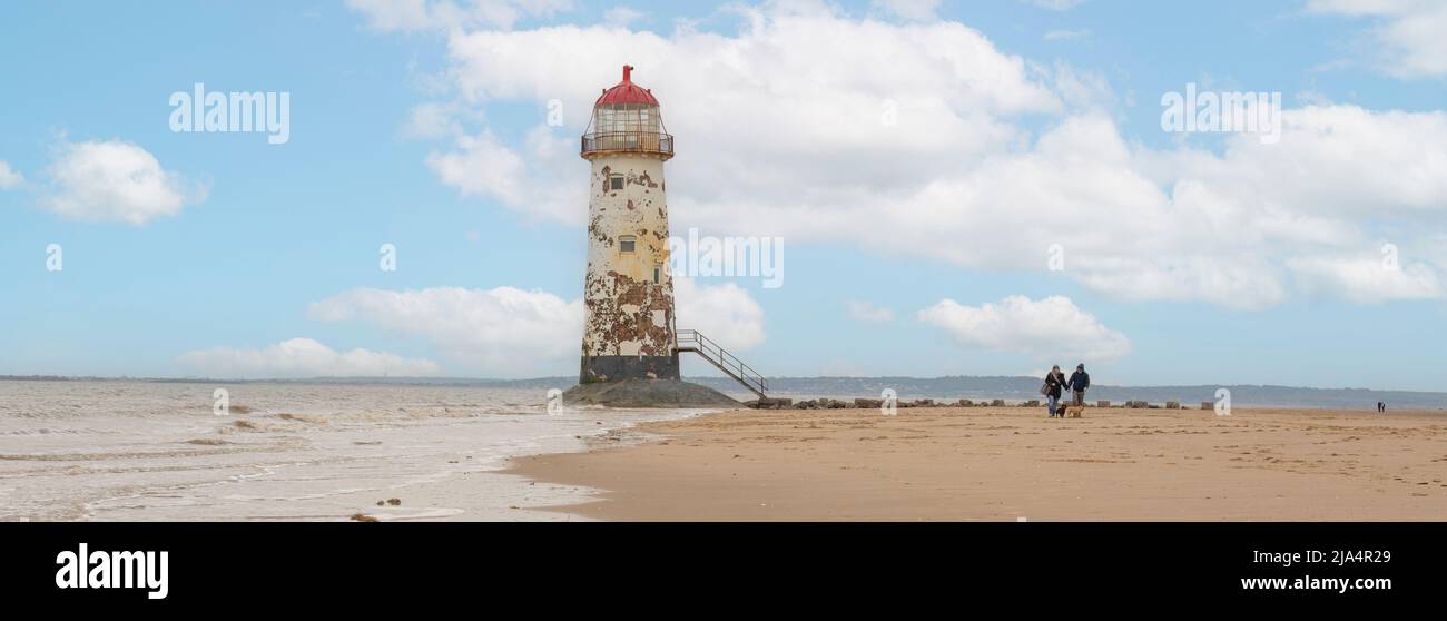 Talacre Beach-Flintshire, pays de Galles du Nord 18 avril 2022 randonneurs de chiens passant le phare de point d'Ayr, tandis que la mer est encore à l'extérieur Banque D'Images