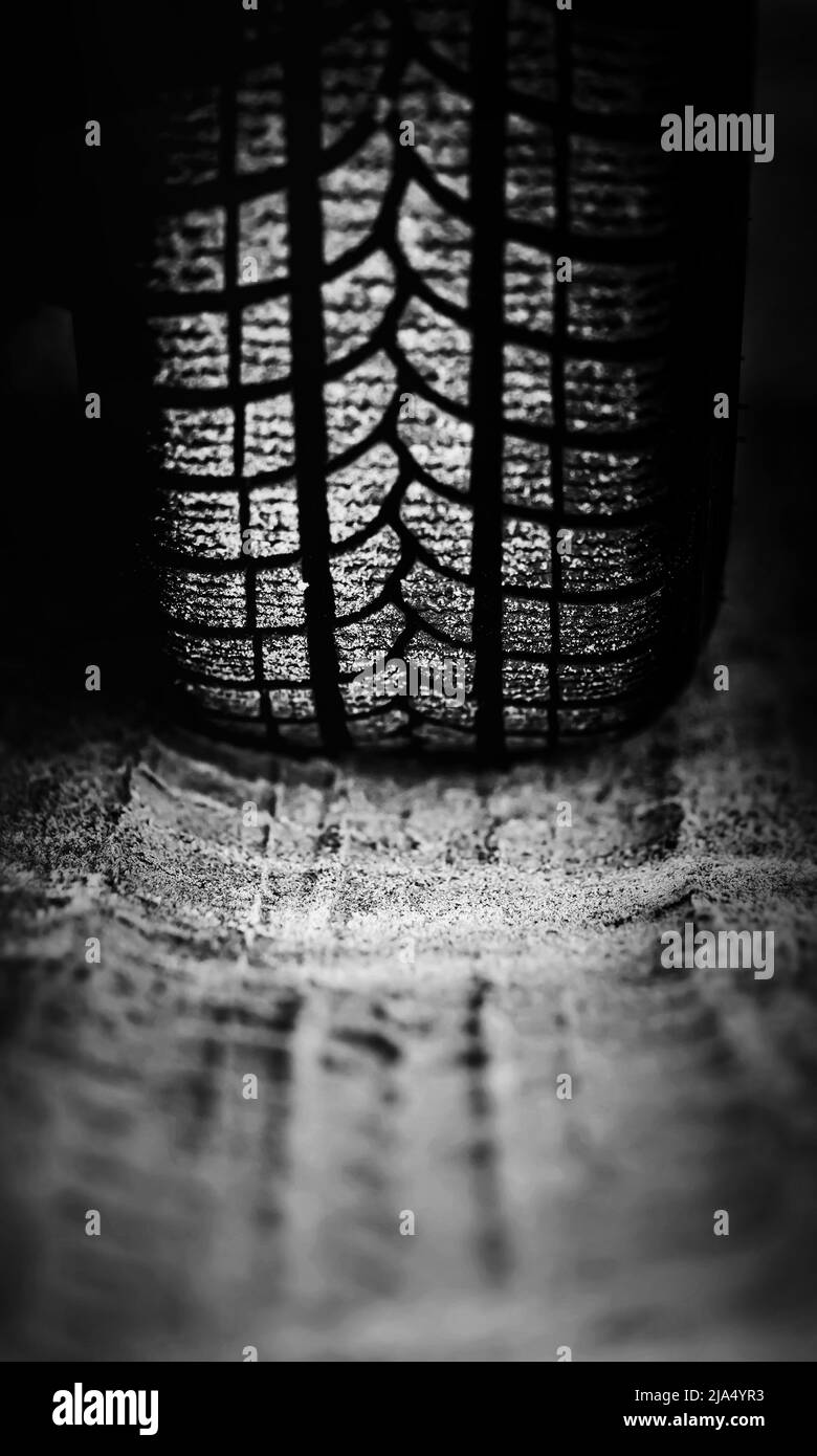 Image en noir et blanc de la roue d'une voiture de tourisme roulant sur une route sablonneuse. Conduite tout-terrain. Banque D'Images