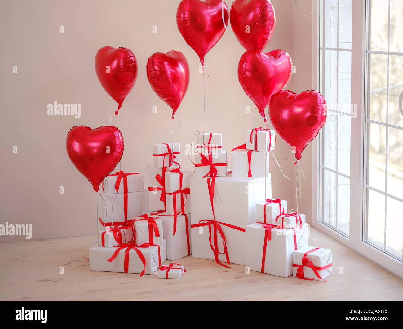 Boîtes cadeau blanches avec ballons en forme de coeur dans le salon blanc près de la fenêtre. Vacances professionnelles, concept de mère, Saint-Valentin, anniversaire. Banque D'Images