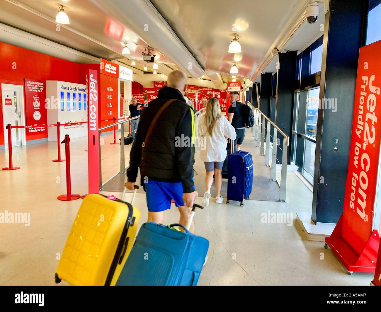 Les voyageurs arrivent avec leurs valises au terminal des départs de l'aéroport de Leeds Bradford pour leurs vacances. Les passagers marchent pour enregistrer leurs bagages. Banque D'Images