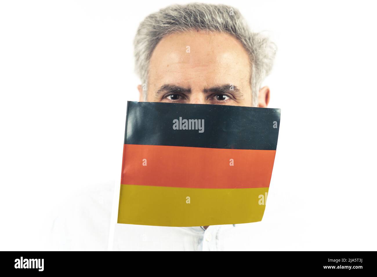Portrait en studio isolé d'un homme âgé caucasien portant un drapeau allemand couvrant son visage. Photo de haute qualité Banque D'Images