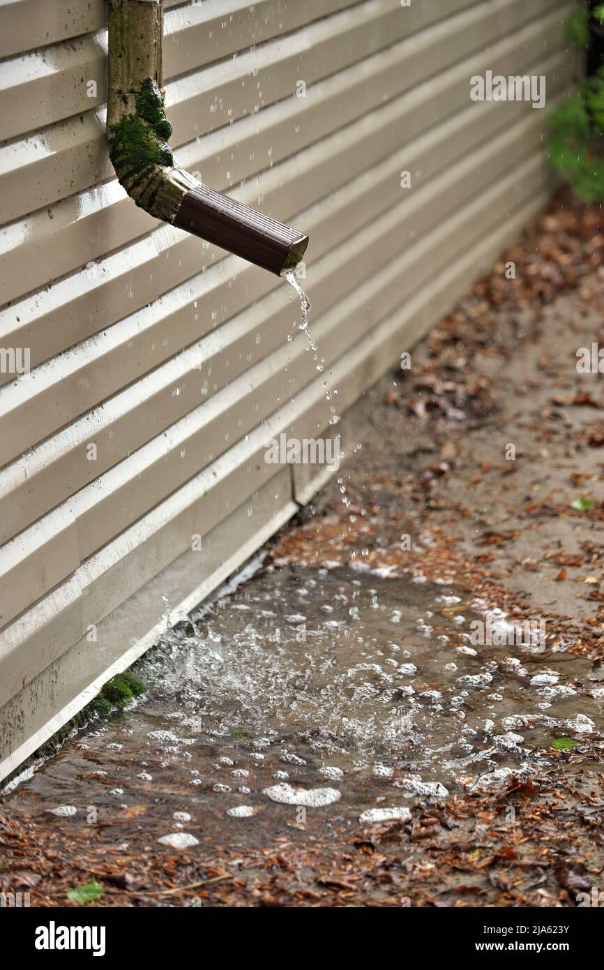 L'eau de pluie coule d'un court déversoir sur le côté de la maison la mise en commun par la fondation Banque D'Images