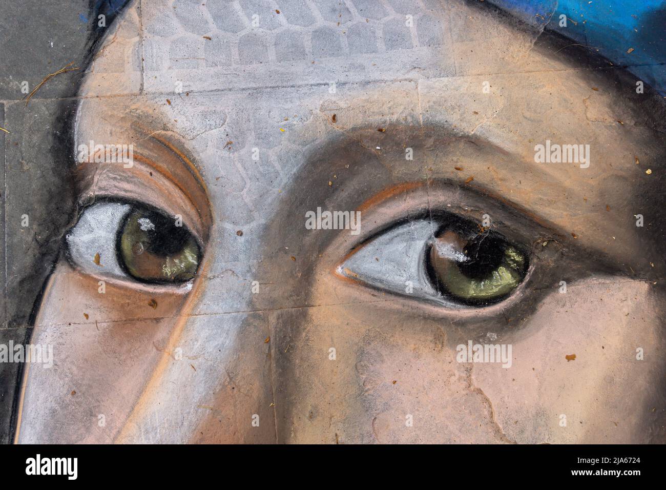 Grado, Italie - 8 juillet 2021: La peinture de rue de la fille, yeux brun foncé et coiffures bleues, fait avec la peinture sur asphalte Banque D'Images