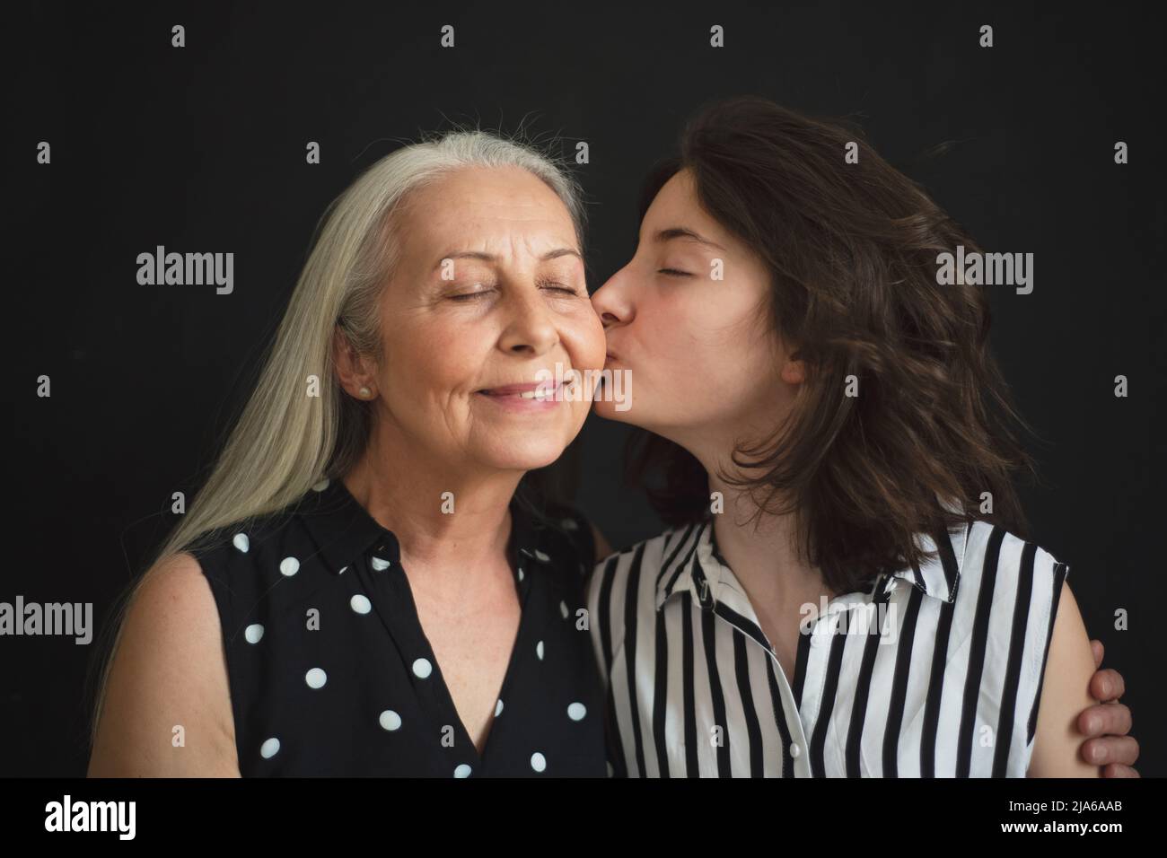Portrait d'une grand-mère âgée avec sa petite-fille l'embrassant sur