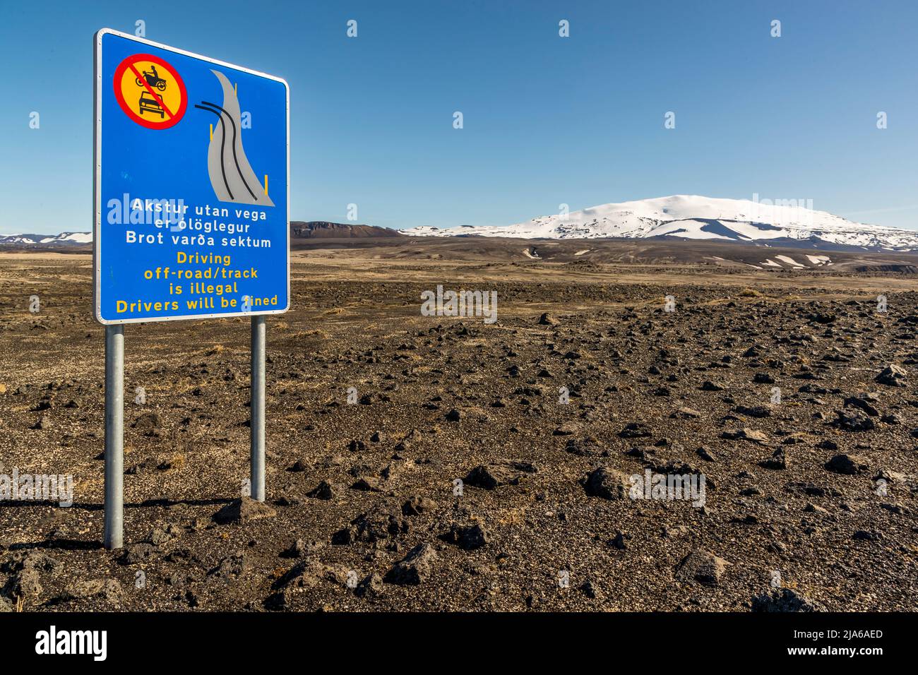 Un panneau le long de la piste montagneuse Landmannaleið (F225) interdit explicitement de rouler hors route : „Akstur utan vega er ólöglegur / Brot varða sektum“ – „Rouler hors route/piste est illégal / Les conducteurs seront sanctionnés“. En arrière-plan s’élève le volcan Hekla, haut de 1 491 mètres, qui, avec plus de 20 éruptions documentées depuis la colonisation de l’Islande vers l’an 1210, compte parmi les volcans les plus actifs du pays. Banque D'Images