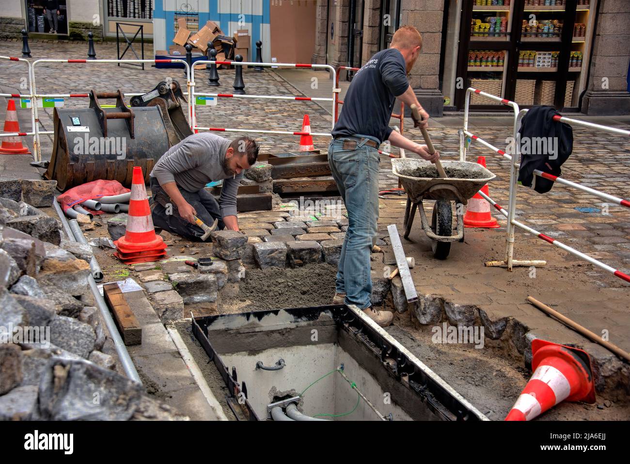 Dinan, France – 12 avril 2022 : rue pavée. Les travailleurs préparent une table de sable de ciment pour le remaplage de la pierre extraite de l'allée. Banque D'Images