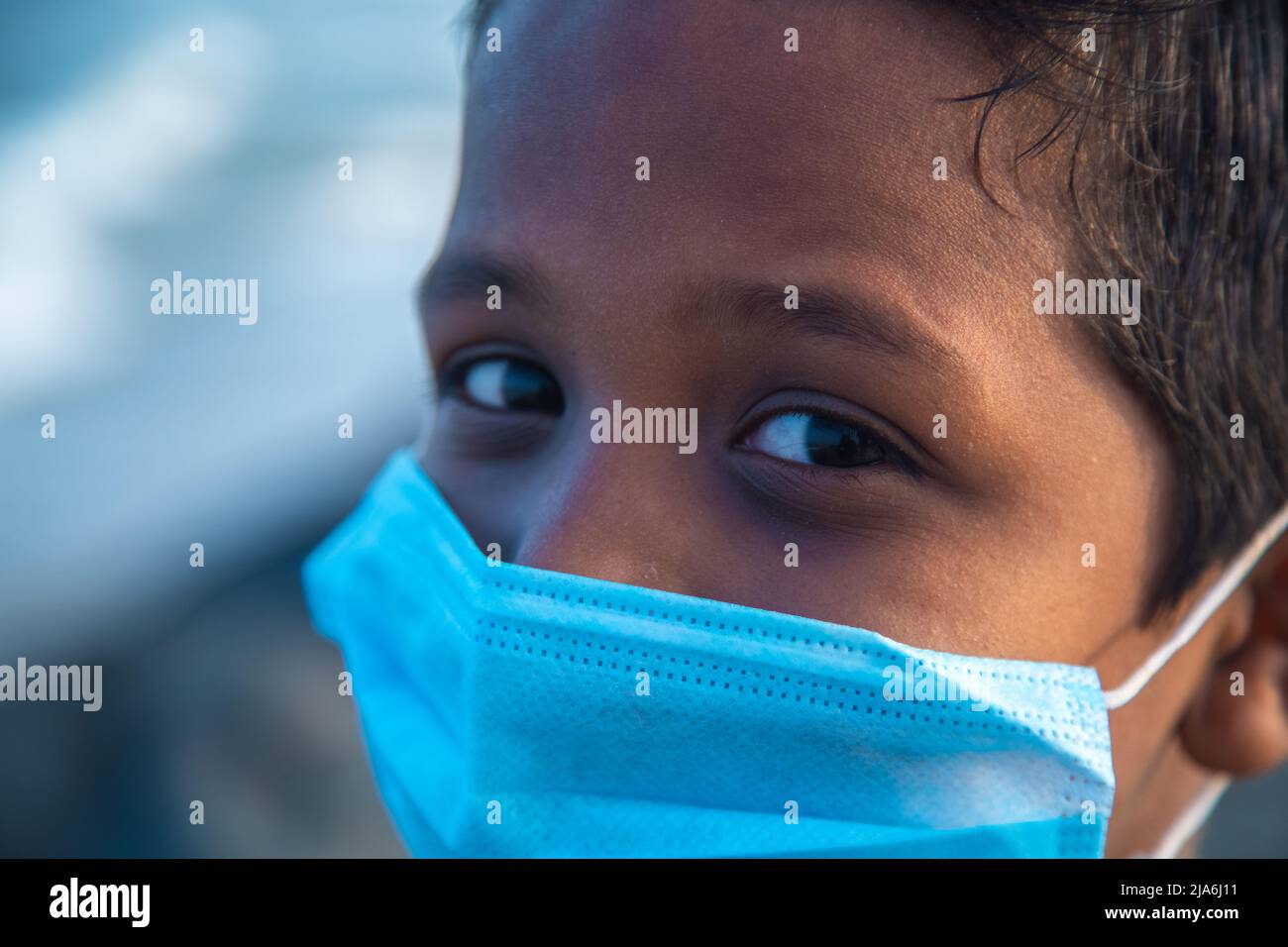 Garçon assis seul sur la plage avec un masque médical - garçon indien triste - garçon asiatique de 8-10 ans. Banque D'Images