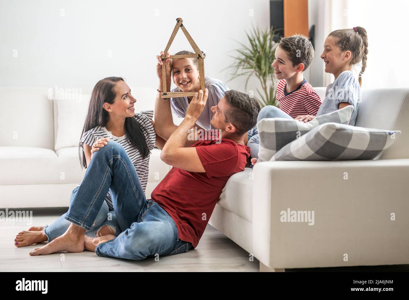 Le père tient un silhoutte d'une maison d'un mètre pliant en bois tandis que les filles sourit à travers elle et la famille rit. Banque D'Images