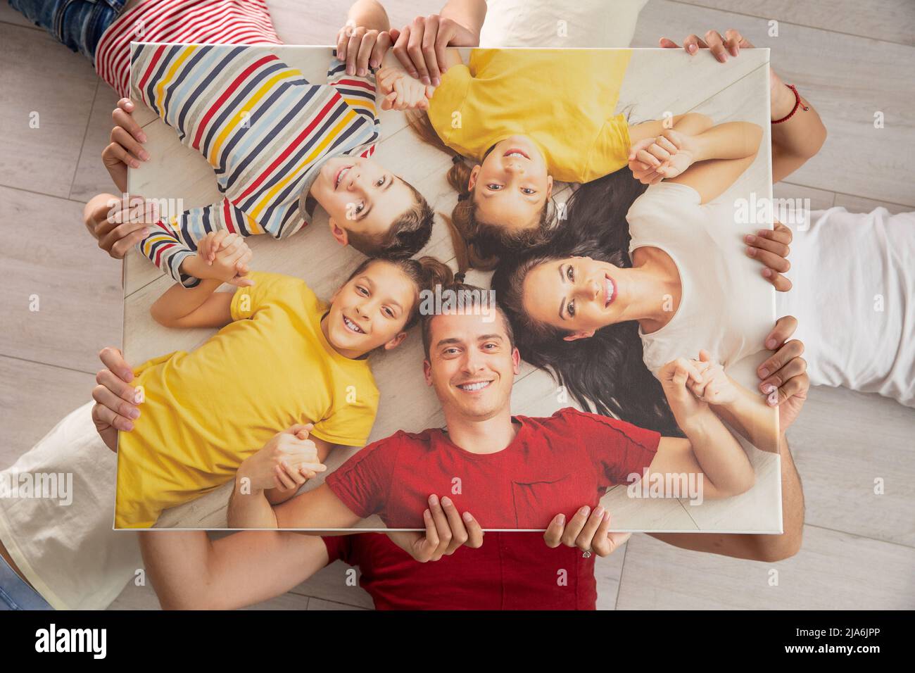 La famille tient la même image d'elle-même en étant couché sur le sol, souriant. Banque D'Images