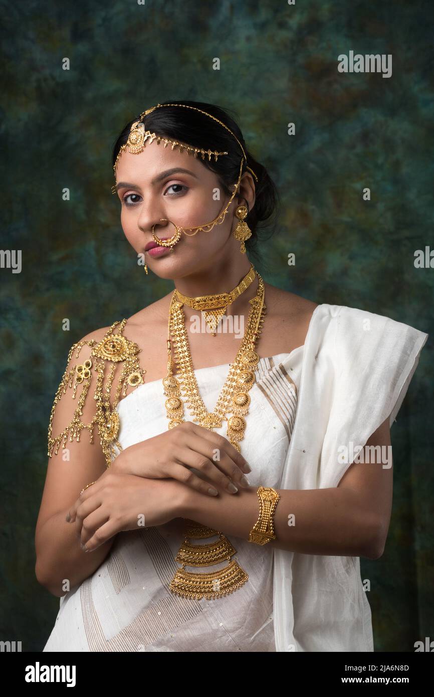 Modèle féminin indien portant un Saree blanc et bijoux en or arborant un look saree traditionnel bengali ou look binodini, modèle saree, ethnique indienne Banque D'Images