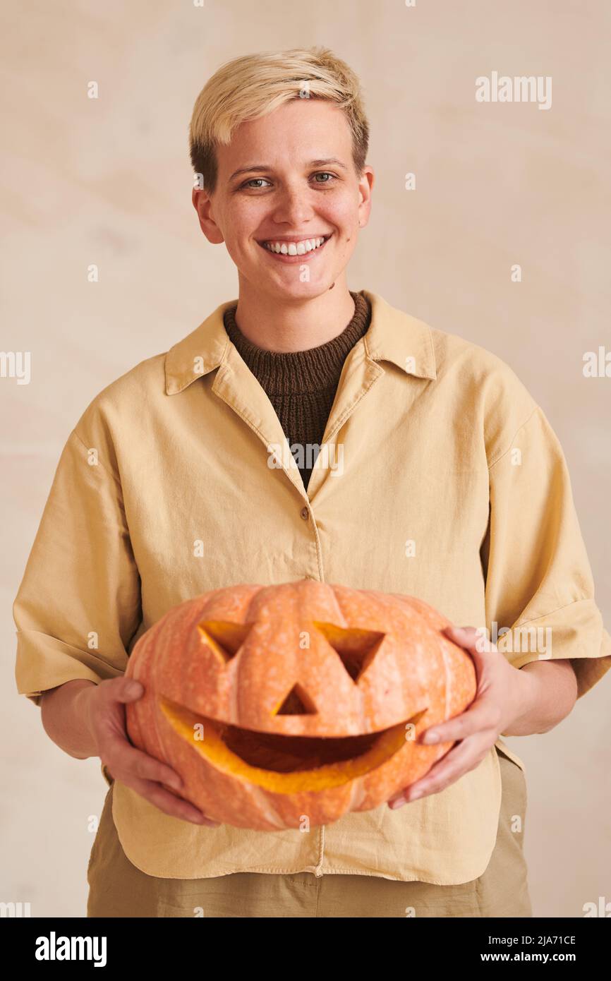 Portrait d'une jeune femme positive avec des cheveux blonds tenant la citrouille d'Halloween contre un arrière-plan isolé Banque D'Images