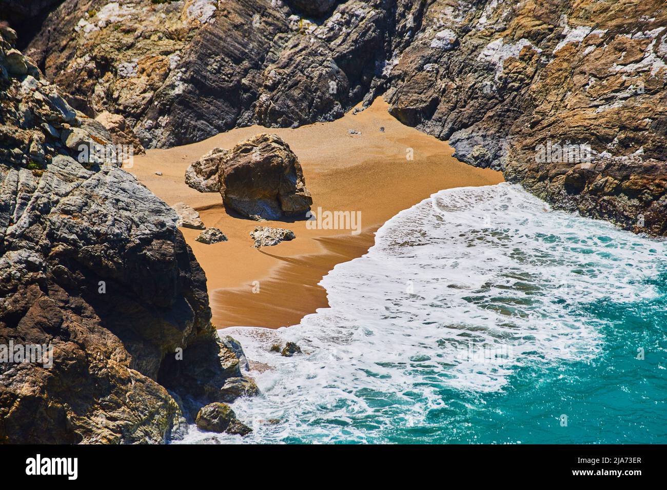 Plage sur l'océan avec plage de sable entourée de rochers Banque D'Images