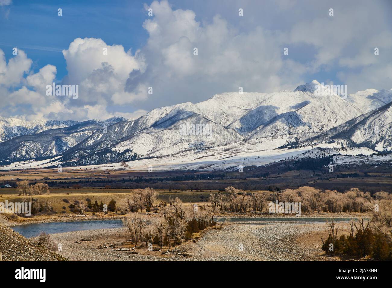 Belles montagnes blanches enneigées avec champs de source et rivière en premier plan Banque D'Images