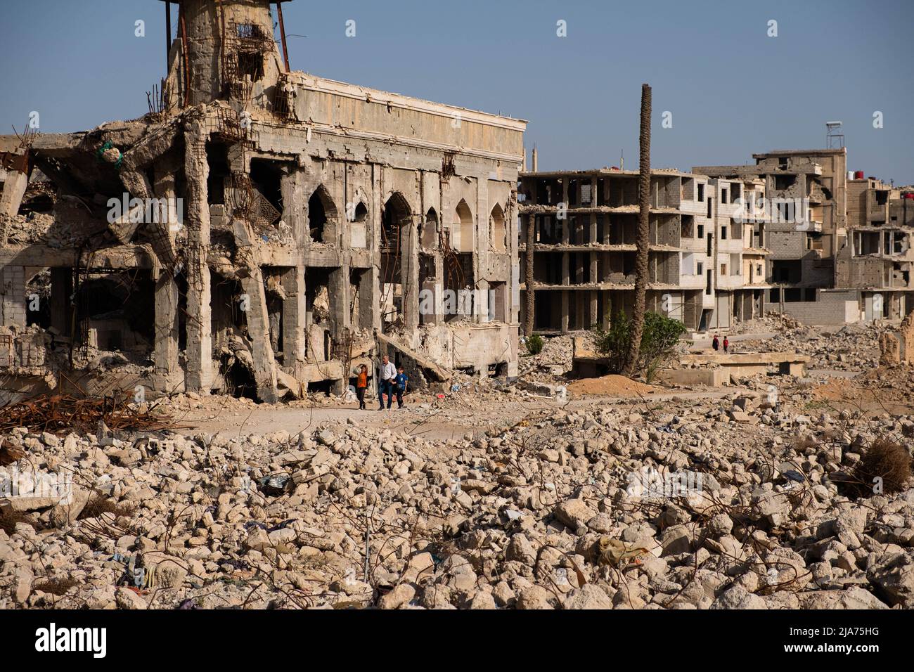 Darayya, Syrie - avril 2022 : une famille qui marche à travers des ruines dans une ville détruite après la guerre civile syrienne. Banque D'Images