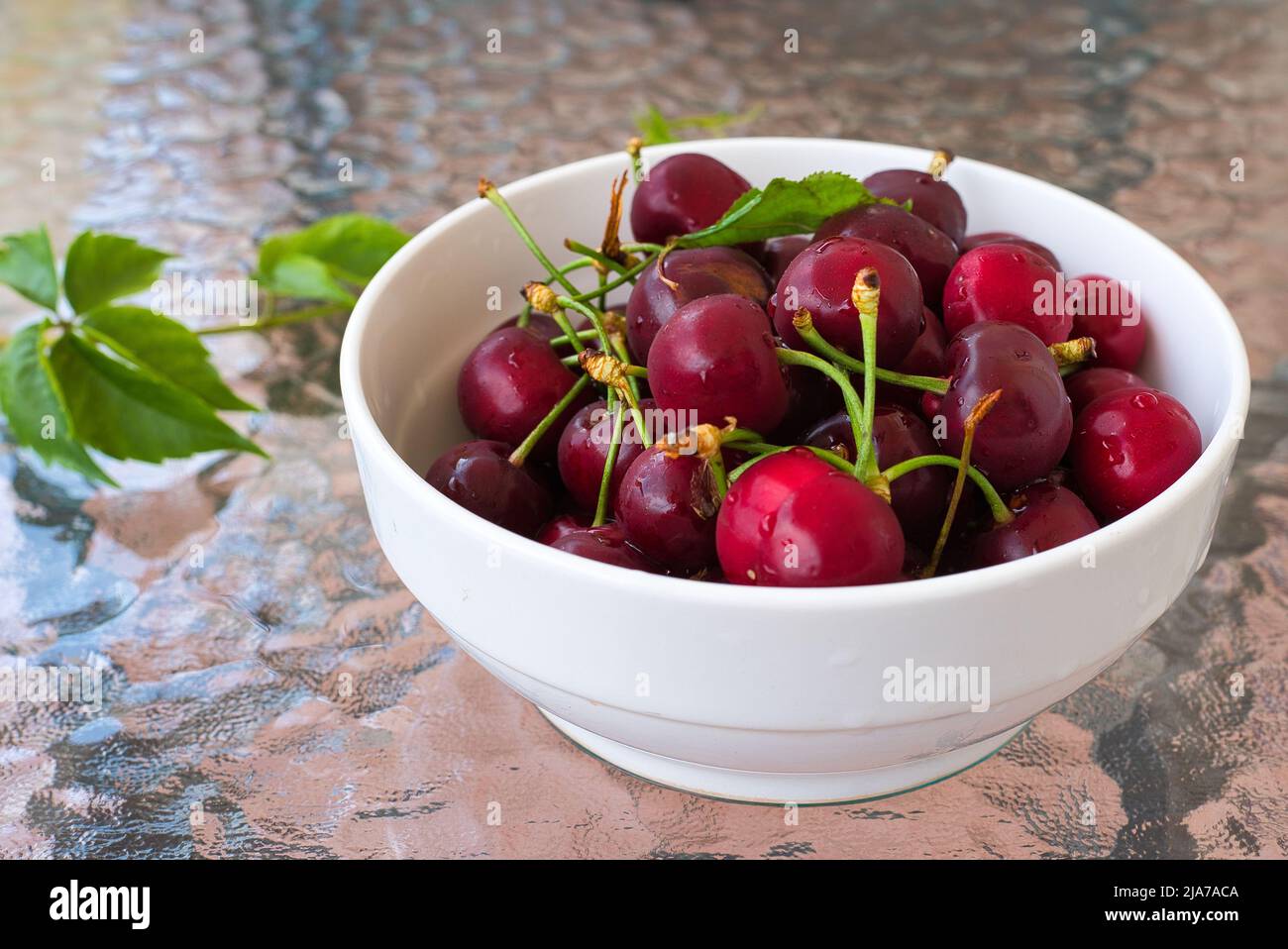 Cerises douces rouges fraîches, dans un panier en osier sur fond de bois Banque D'Images