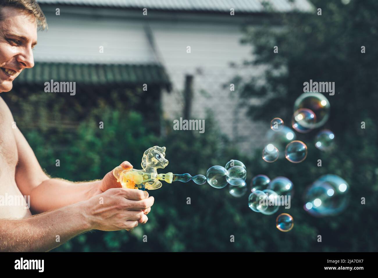 Pistolet à bulles de savon poney, souffleur. Fête pour les enfants. Filles, chidren jouant drôle de jeu de famille avec papa, père. Activités de plein air en été dans le vert p Banque D'Images