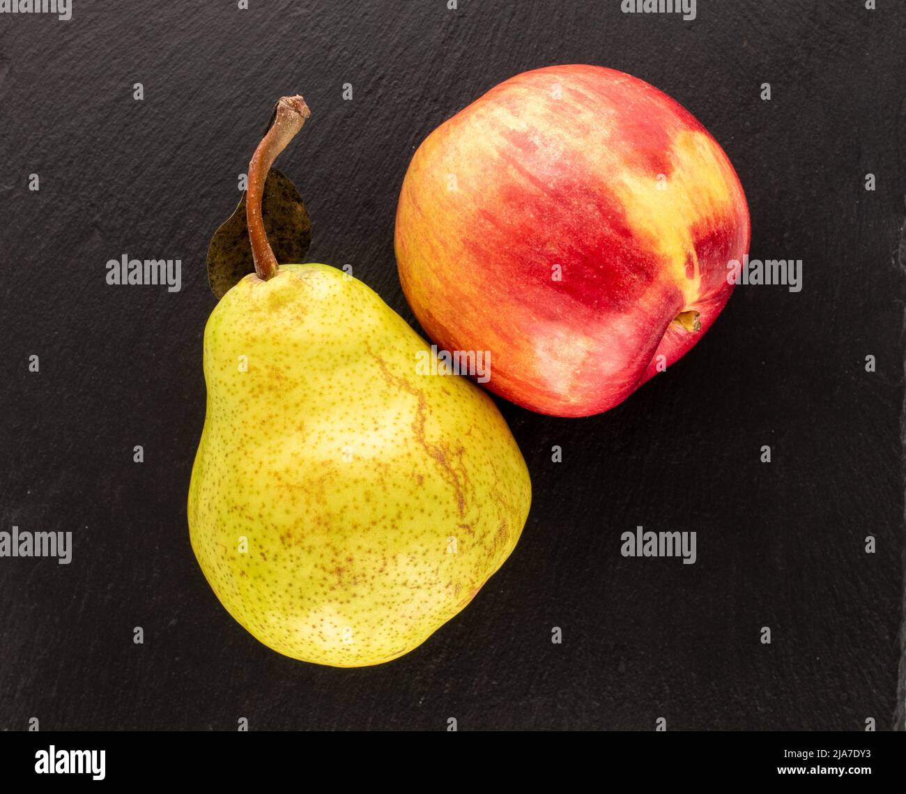 Une poire biologique juteuse et une pomme sur une pierre d'ardoise, gros plan, vue du dessus. Banque D'Images