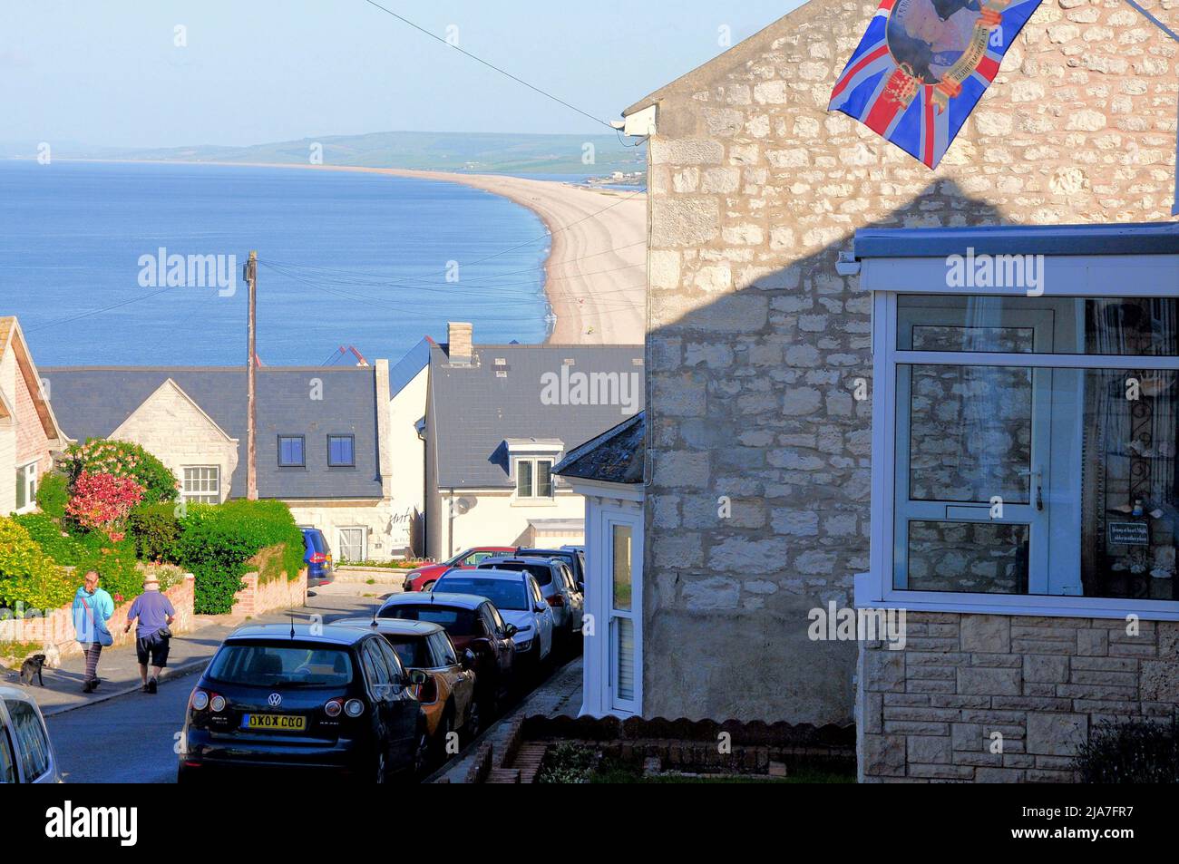 Île de Portland. 28th mai 2022. Météo Royaume-Uni. Les gens se promènent pour marcher leurs chiens sur la plage de Chesil, sur l'île de Portland, où le drapeau du Jubilé de platine de la Reine flotte à l'extérieur d'une maison. Crédit : stuart fretwell/Alay Live News Banque D'Images