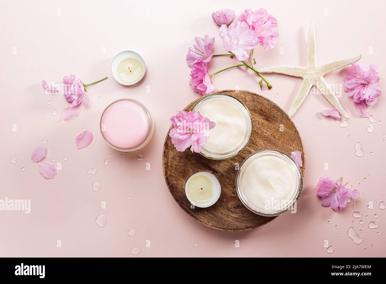 Crème de soin du corps naturelle et fleurs de cerise rose. Pose à plat. Banque D'Images