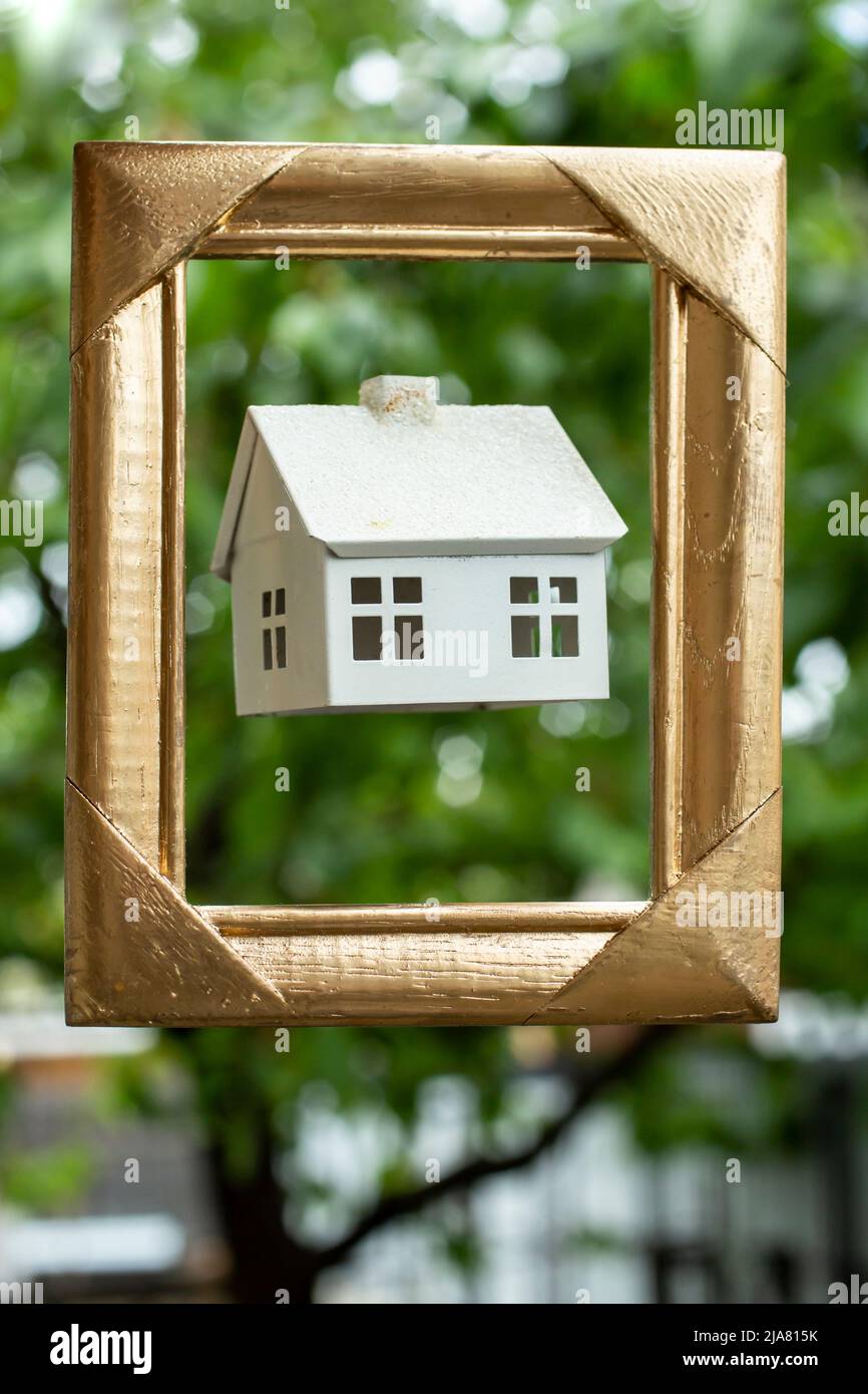 présentation d'une maison modèle blanche dans un cadre doré avec des arbres en arrière-plan. Banque D'Images