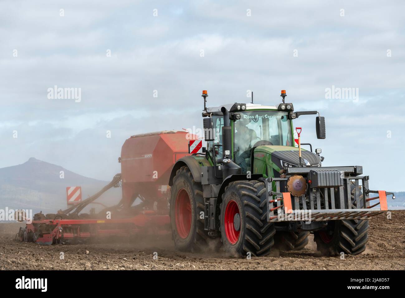 Un tracteur vert Fendt et un semoir à disque Red Horsch semis d'orge sur un champ labouré sec en vue de Bennachie dans l'Aberdeenshire, en Écosse Banque D'Images