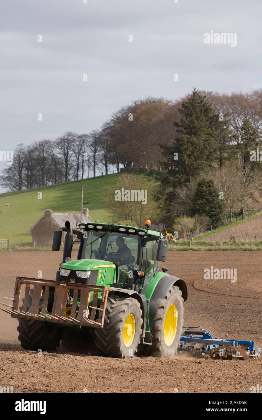 Un tracteur John Deere 6175R tractant un scarificateur sur un champ labouré en préparation pour semer une récolte céréalière Banque D'Images