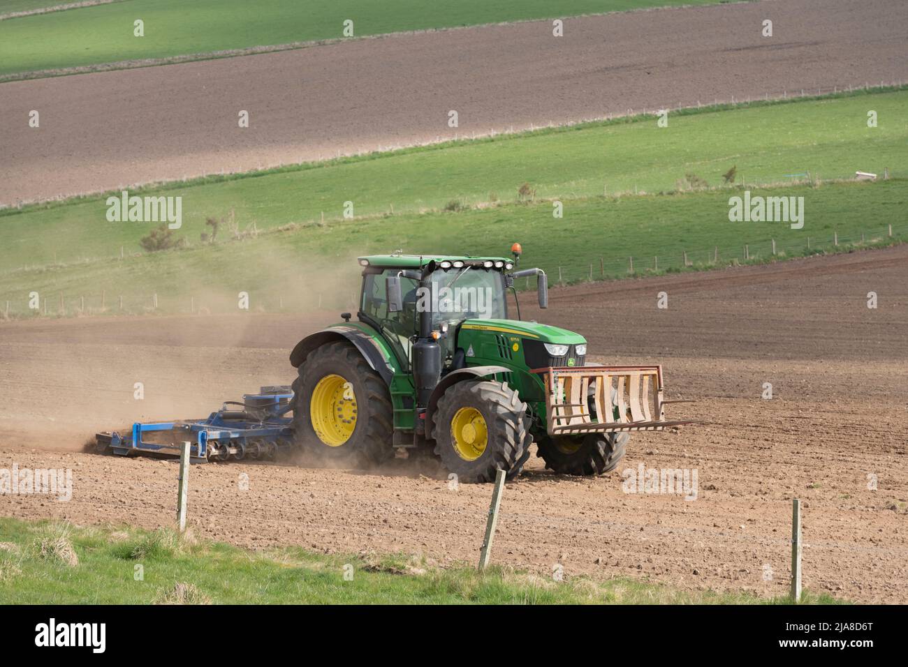 Un tracteur John Deere vert tirant un scarificateur au-dessus d'un champ labouré sur des terres agricoles d'Aberdeenshire Banque D'Images