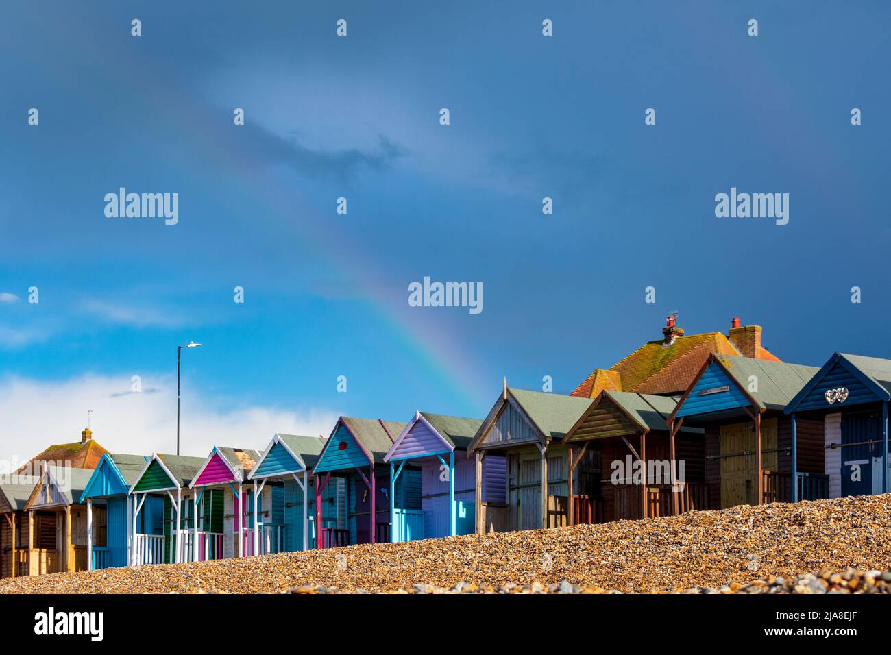 Un arc-en-ciel vu au-dessus d'une rangée de cabanes traditionnelles britanniques de plage, un emplacement récent vu dans le drame romantique à l'adolescence de Netflix, à l'arrivée, « Heartbuck ». Banque D'Images