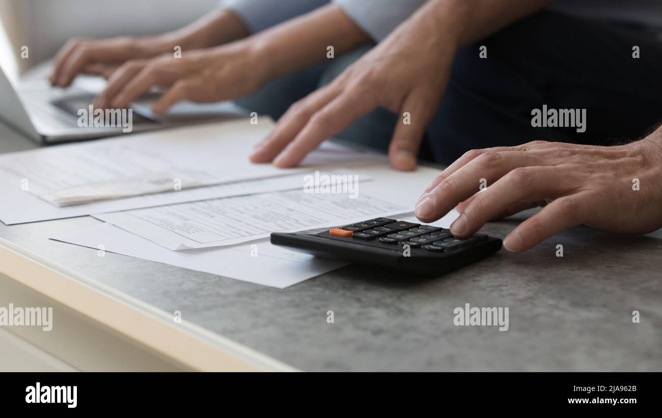 Gros plan mains couple âgé travailler avec des papiers à l'aide de la calculatrice d'ordinateur portable Banque D'Images
