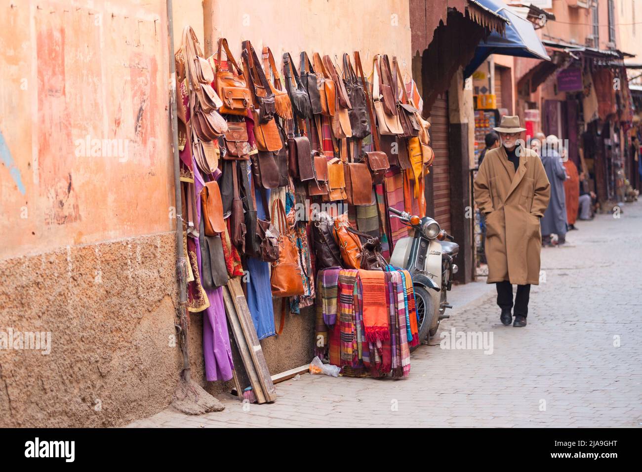 Homme en chapeau et manteau marchant à Souk, Marrakech, Morroco. Articles en cuir à vendre dans la vieille médina Banque D'Images