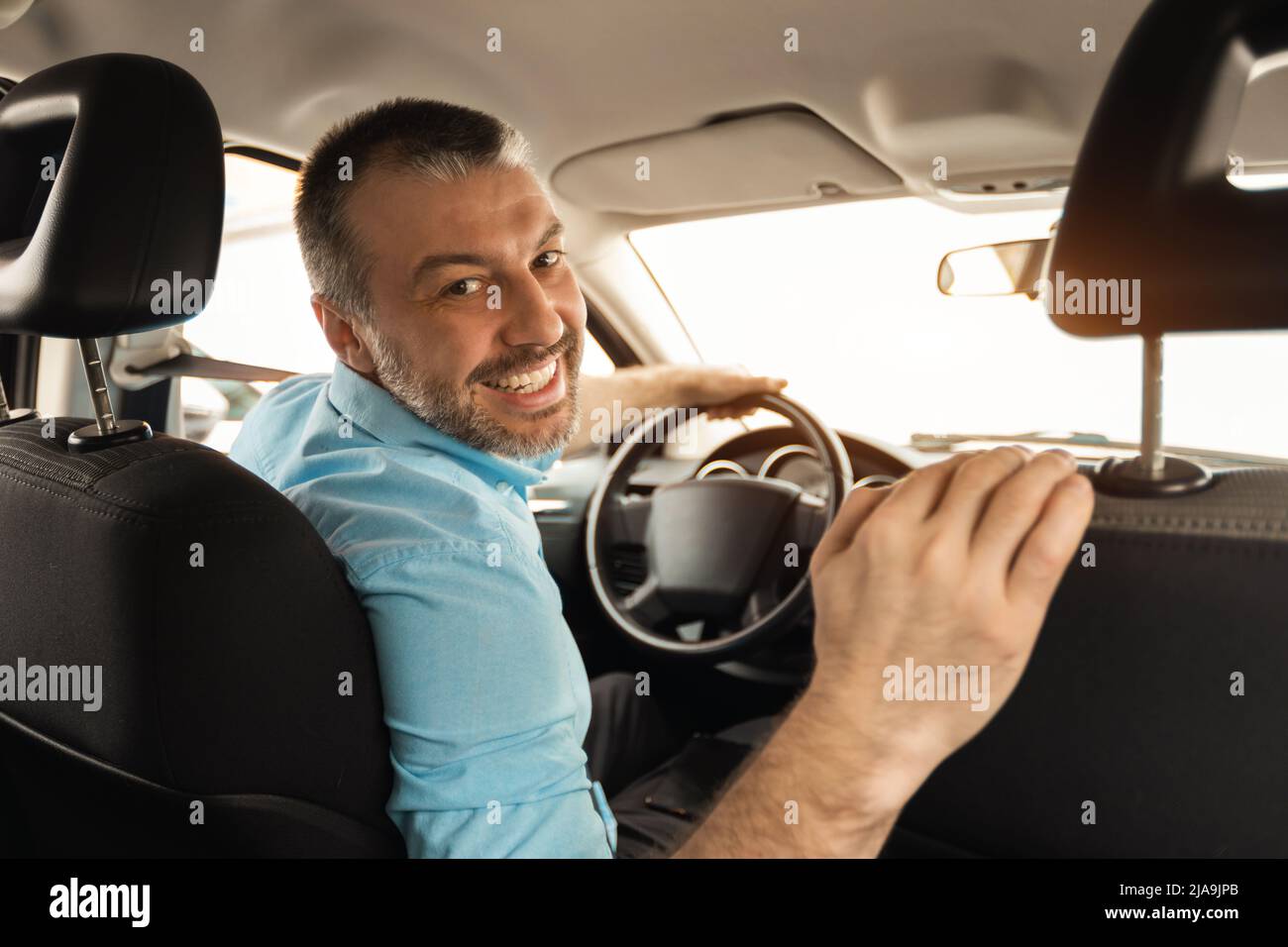 Homme souriant conduisant une nouvelle voiture en ville Banque D'Images