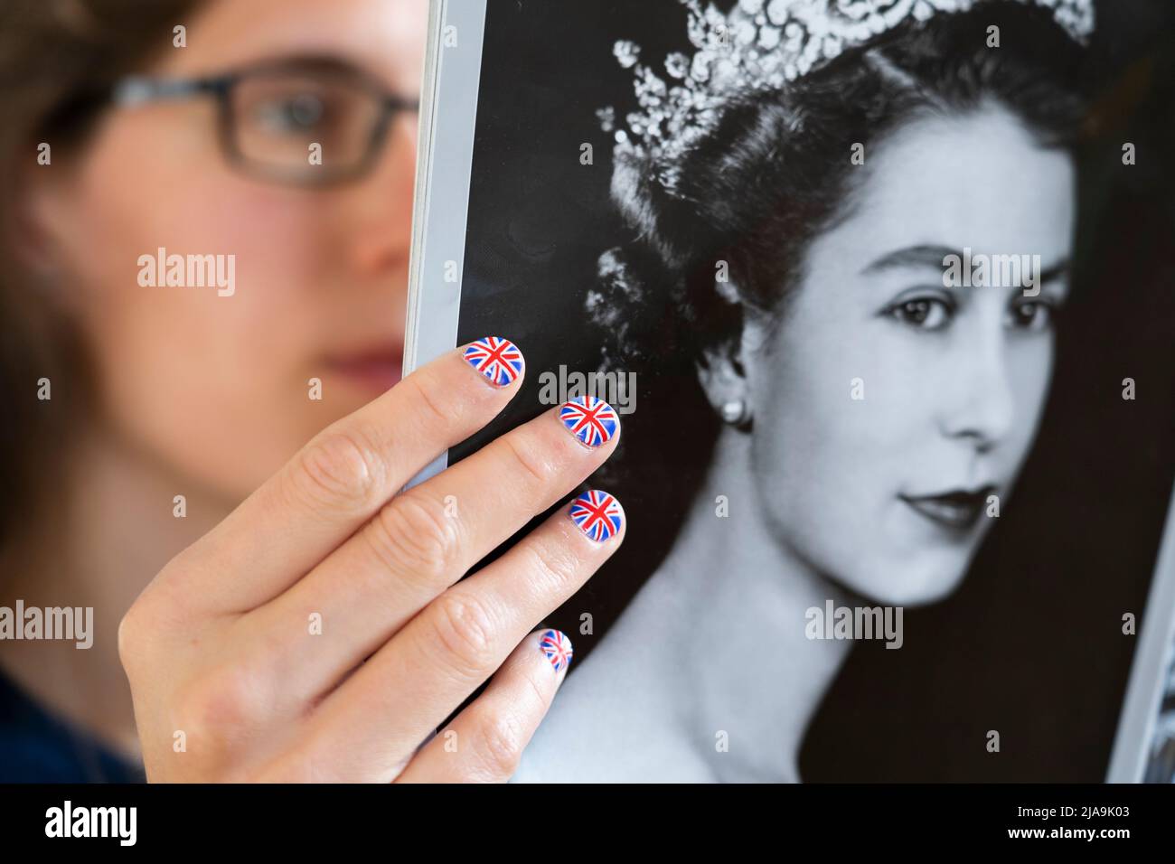 Fan avec les ongles peints avec le drapeau britannique tenant une copie du magazine OK avec un portrait d'une jeune Elizabeth II Jubilé de platine juin 2022 Banque D'Images
