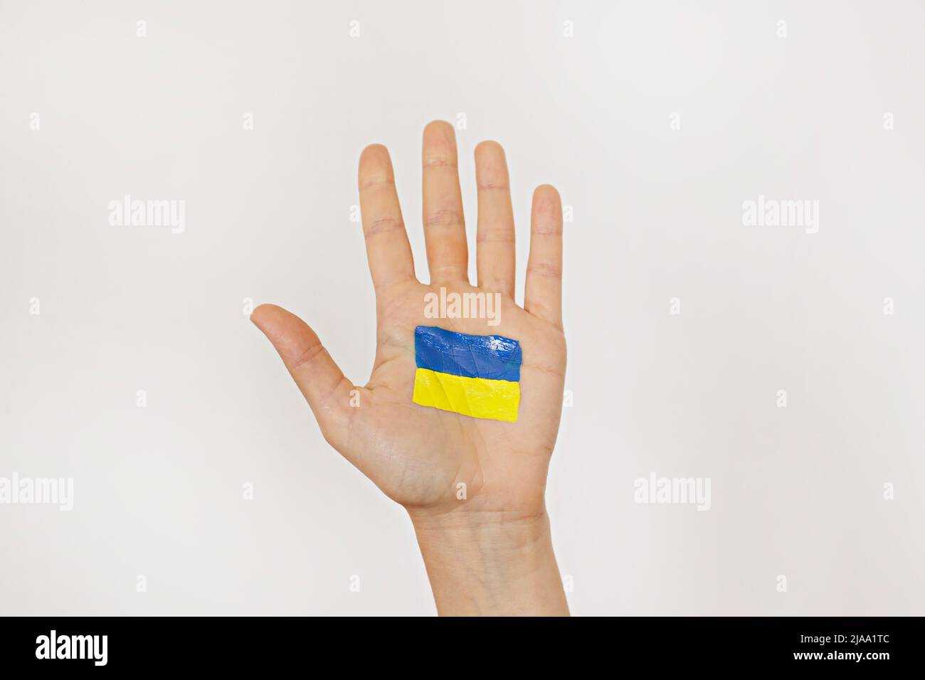 Gros plan sur la paume de la main d'une femme avec le drapeau national ukrainien dessiné dessus. Une main levée dans un soutien de l'Ukraine. Copier l'espace pour le texte, backgro Banque D'Images