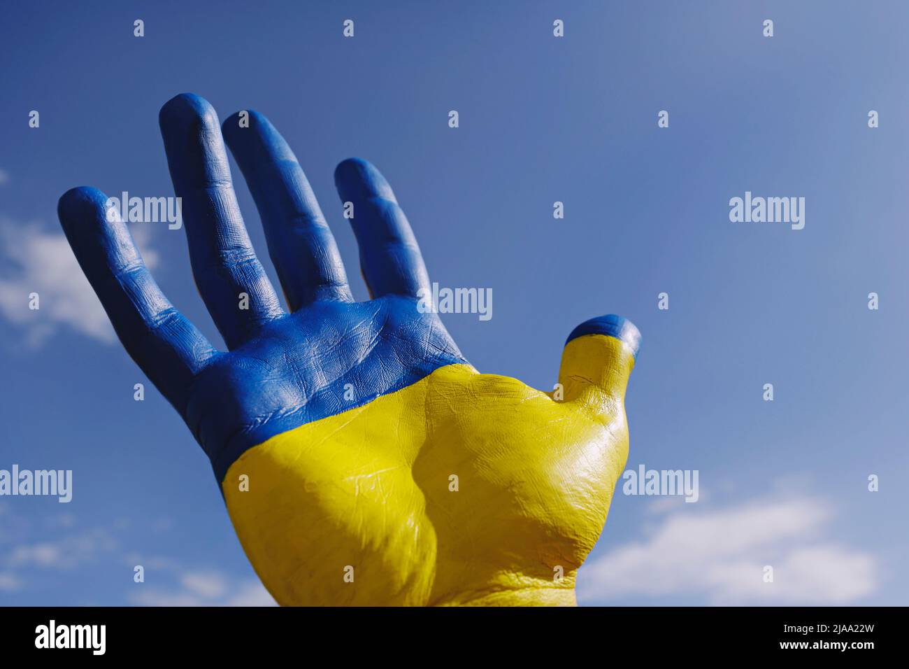 Gros plan sur la main d'un homme illuminée par le soleil peint en couleurs du drapeau national ukrainien. .Une main levée sur fond bleu ciel comme symbole de sup Banque D'Images