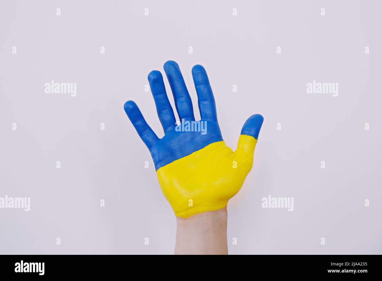 Gros plan d'un homme peint à la main dans les couleurs du drapeau national ukrainien. Une main soulevée sur un arrière-plan blanc isolé comme symbole de soutien et ainsi de suite Banque D'Images