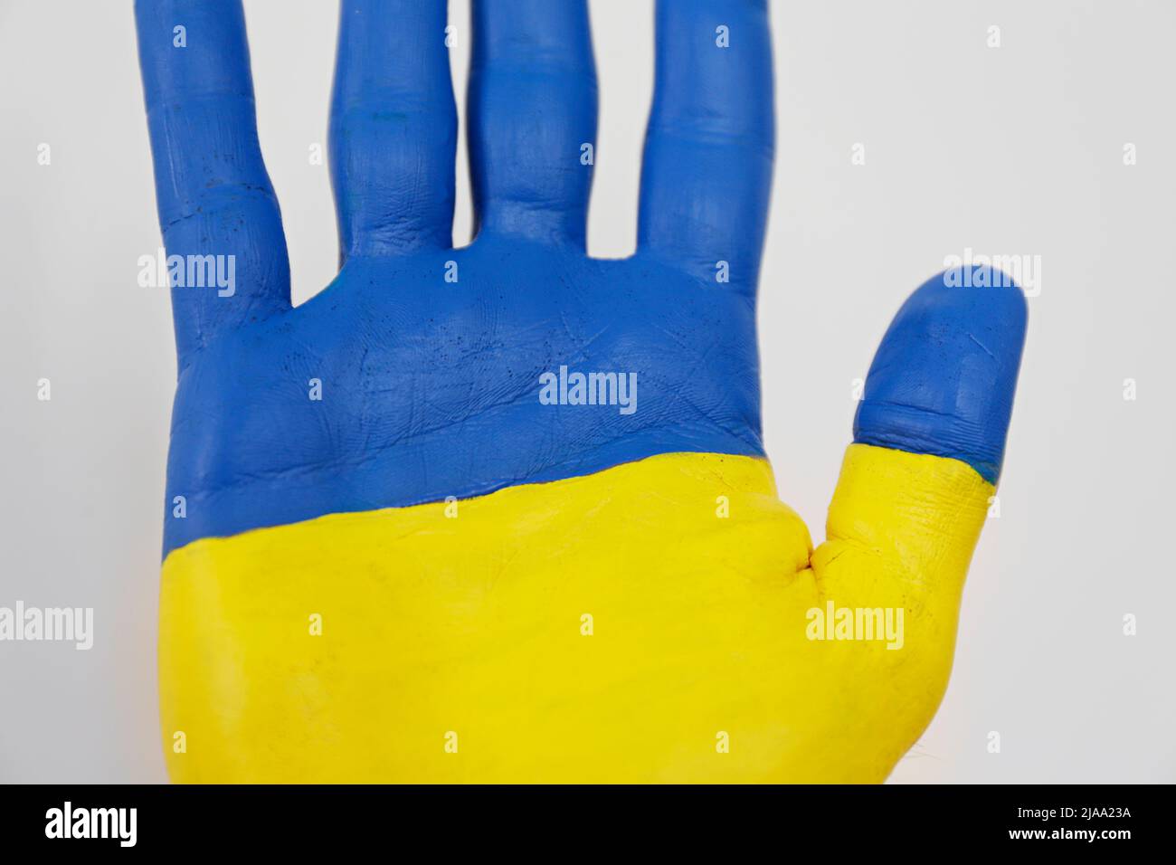 Gros plan d'un homme peint à la main dans les couleurs du drapeau national ukrainien. Une main soulevée sur un arrière-plan blanc isolé comme symbole de soutien et ainsi de suite Banque D'Images