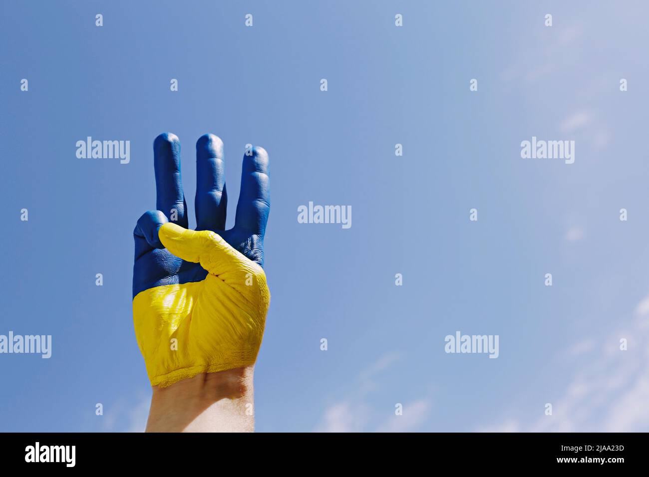 Main de l'homme éclairée par le soleil peint dans les couleurs du drapeau national ukrainien montrant un geste de main trident traditionnel comme un symbole de soutien et de solidari Banque D'Images